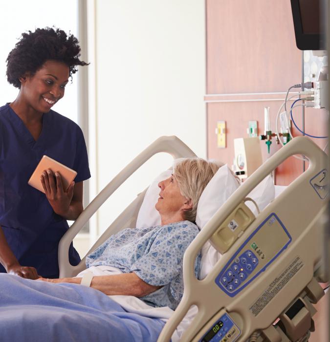 Caregiver answering senior patient's questions in bed.